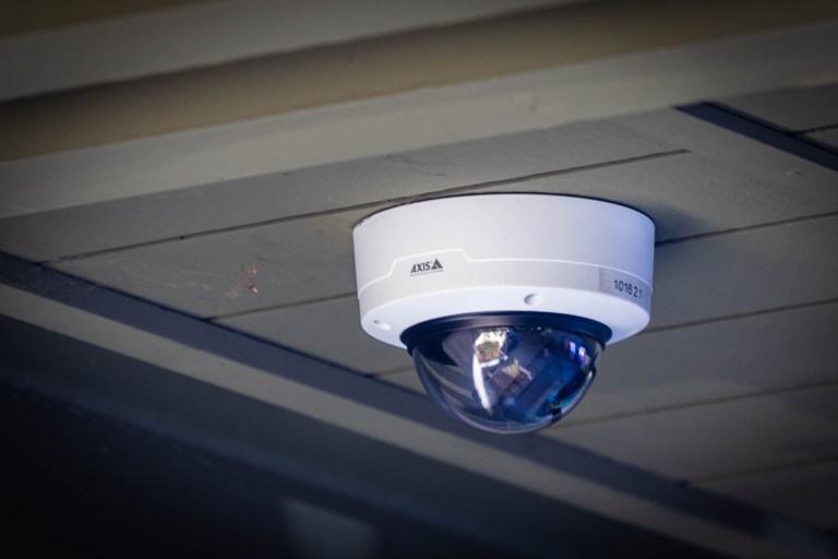 A security camera attached to the ceiling of a building on campus.