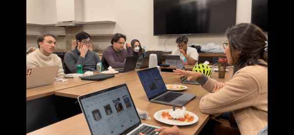 People sit around a conference table with laptops open.