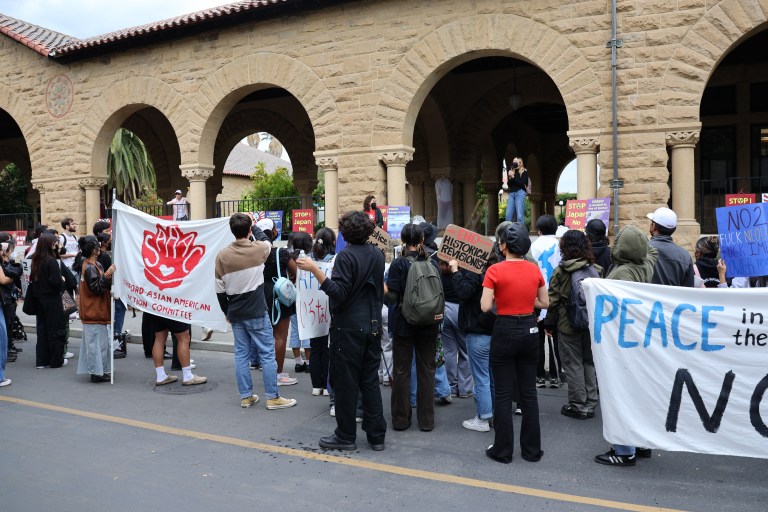 Protests holding signs and banners gather on a street