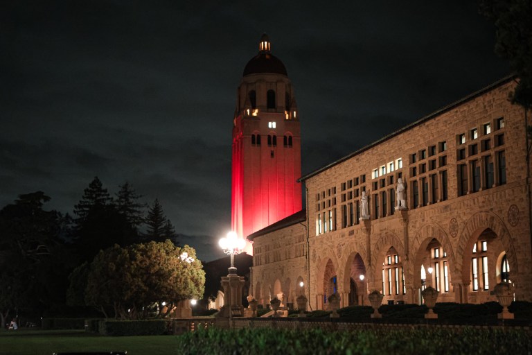 A photo of Main Quad and Hoover Tower, lit up in red.