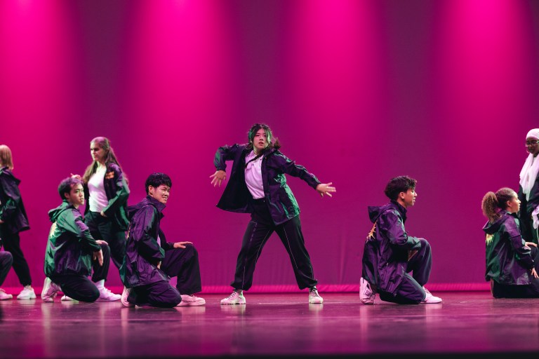 A group of dancers in black dancing on stage.