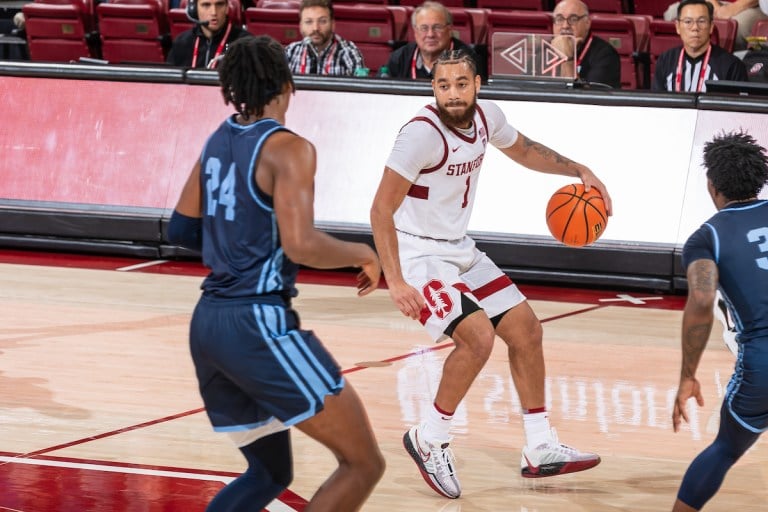 Jared Bynum dribbles a basketball and looks at two San Diego players.