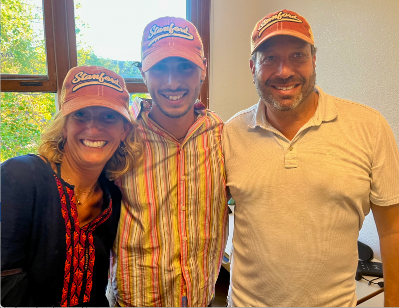 Black stands in between his "chosen father" and "Soul Mama," all three of them wearing Stanford hats.