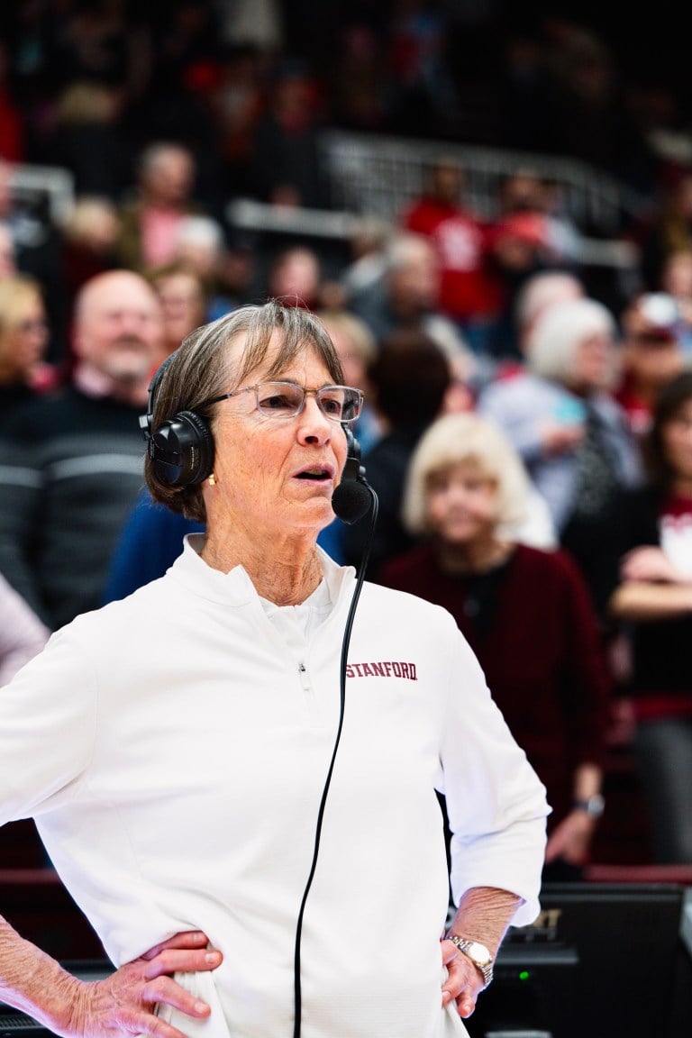 Tara VanDerveer stands on the court with headphones.