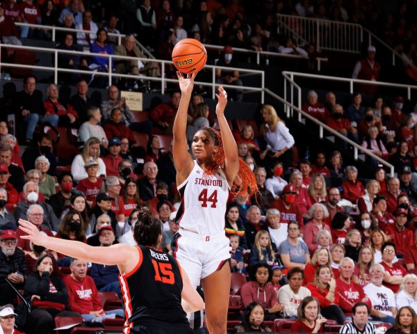 A Stanford player leaps into the air to score as Arizona players crowd from her.