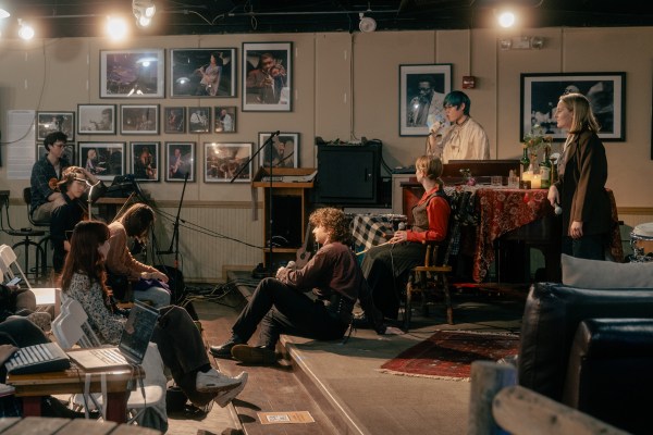 Students perform 'Ghost Quartet' onstage in a coffee shop, while other students look on.