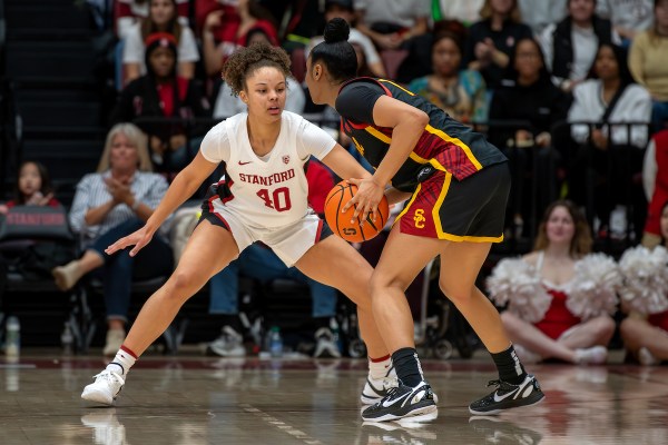 A Stanford player attempts to block a USC player who holds the ball.