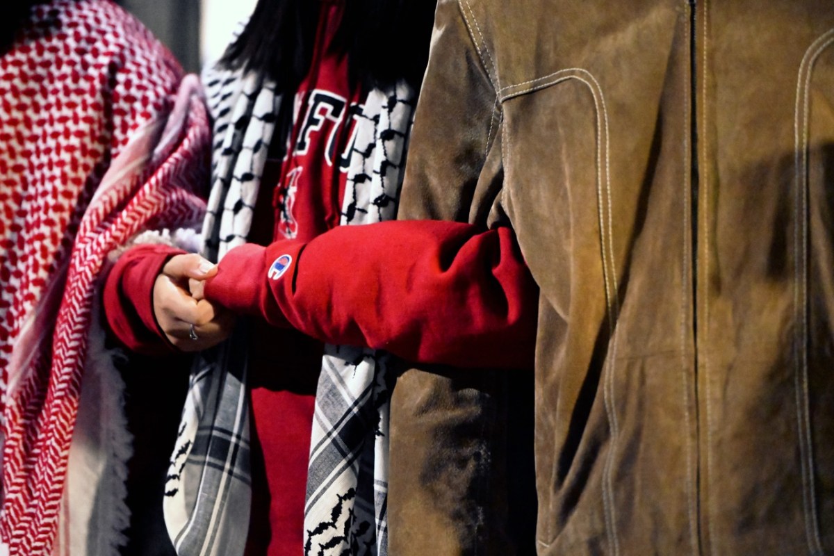 Three students stand with intertwined arms to demonstrate with the pro-Palestine sit-in. 