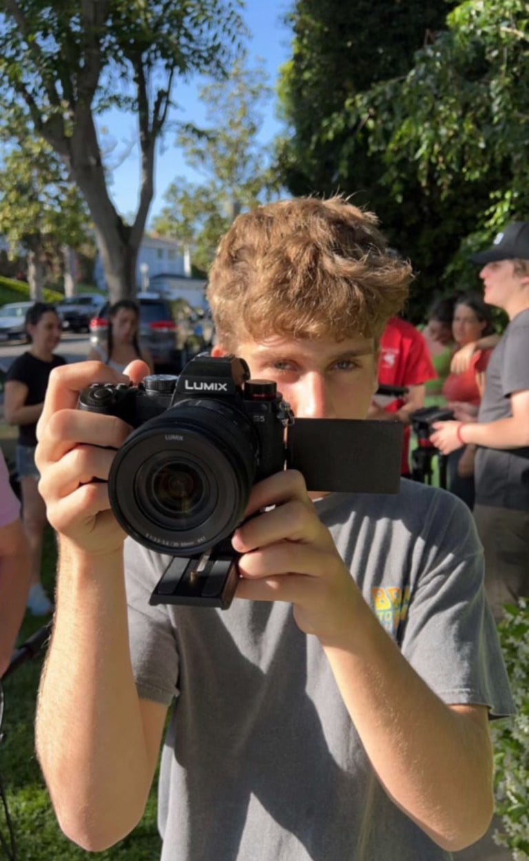 Noah Goldsmith behind a camera pointed at the viewer.