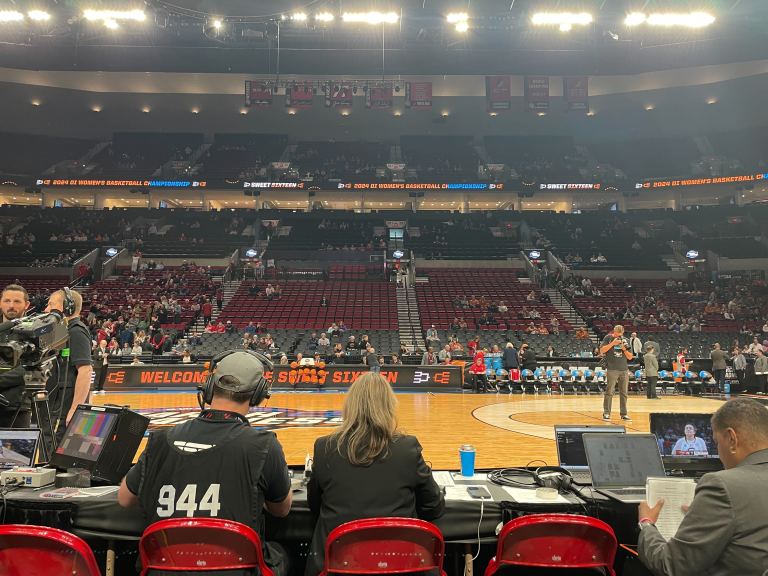 Image of Moda Stadium before the start of the game. Red chairs line a table on the court, and the seats in the stadium appear half-filled as fans file in.