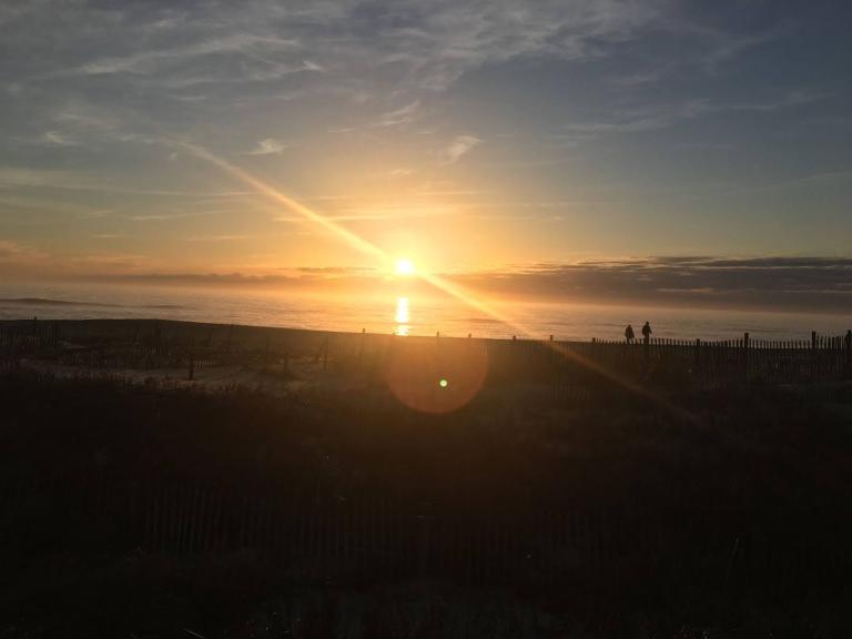 Sunset with silhouettes of people by the beach.