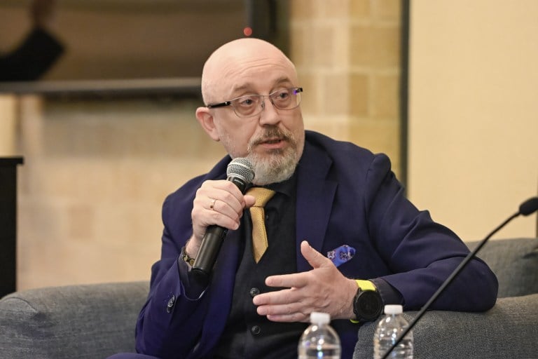 Reznikov holds a microphone speaking to the crowd from a gray armchair.