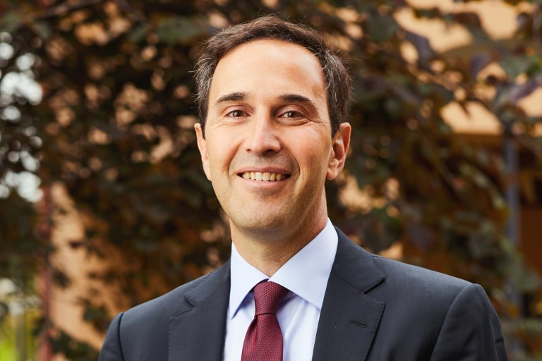 Jonathan Levin smiles in front of foliage.