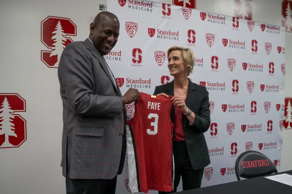 Kate Paye holds basketball jersey with Bernard Muir.