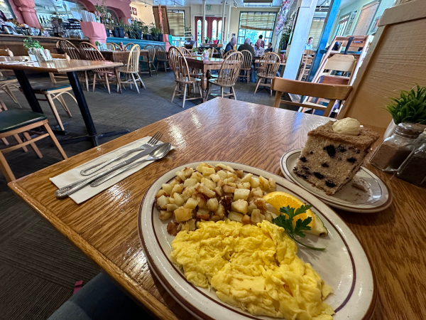 A plate with breakfast, including an omelette and coffee cake, sits in a homey restaurant