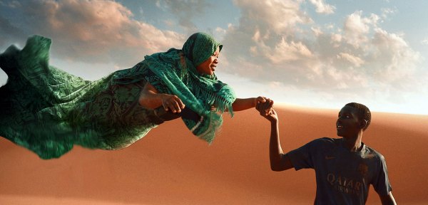 Scene of a woman and a boy in the desert, touching hands.