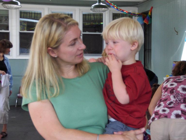 A family photo of a mother, in a green shirt, holding her young son.