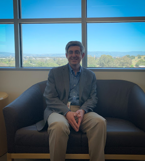 A man in a suit sitting on a couch, before a big window