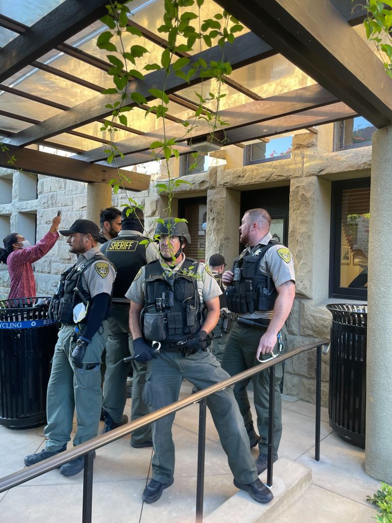 Police officers stand outside a door in Main Quad.