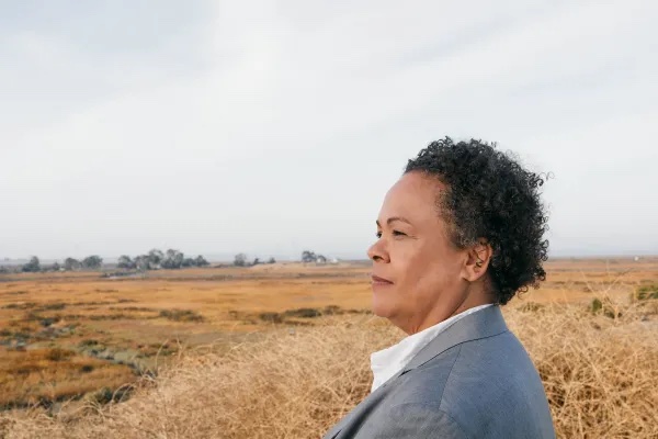 Julie Lythcott-Haims stares at a field with a trail in the background.