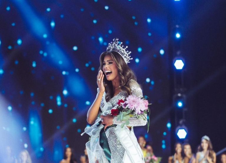 Alma Cooper stands with a bouquet of flowers and a crown onstage after winning the Miss USA 2024 pagaent.