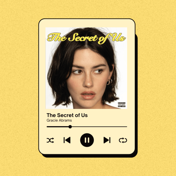 A yellow phone screen displays a Spotify interface and the album cover for Gracie Abrams' album, "The Secret of Us."