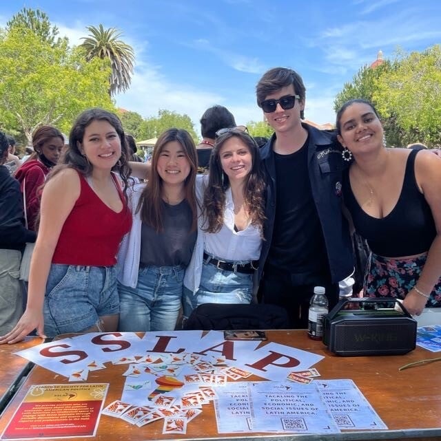 Group of students stands behind a table