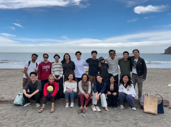 A class of 15 students on a trip to the beach, posing together in two rows