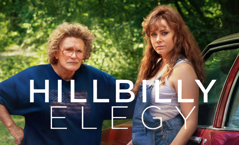 Actresses Glenn Close and Amy Adams stand in front of a car with the text "Hillbilly Elegy" in front of them.