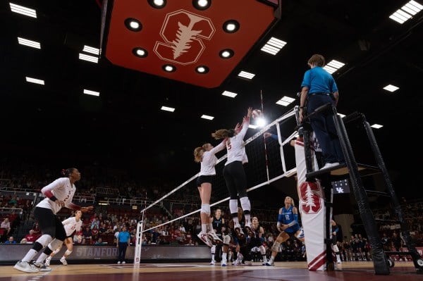 Volleyball players jumping above the net