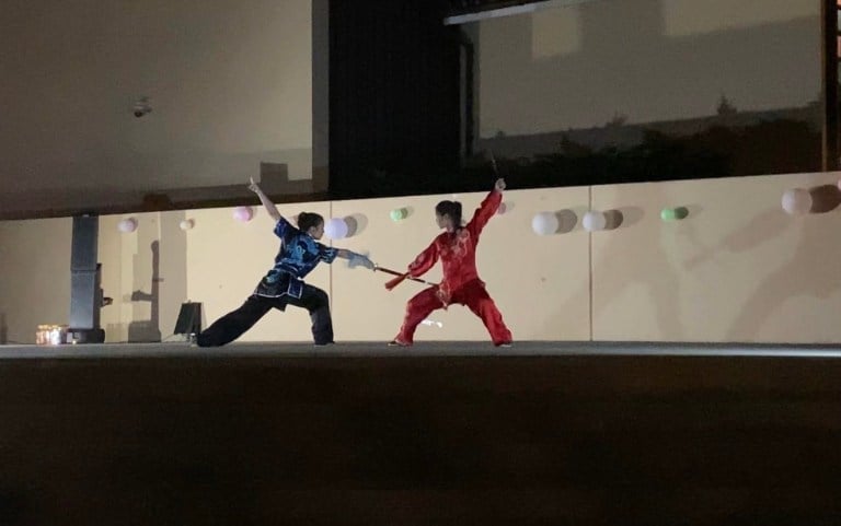 Two people doing wushu on a stage at White Plaza.