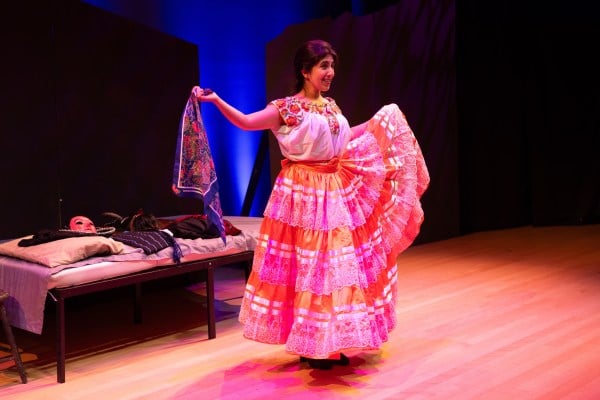 Actress Luna Lau dressed in a bright pink, floral dress dances, smiling out at the audience.