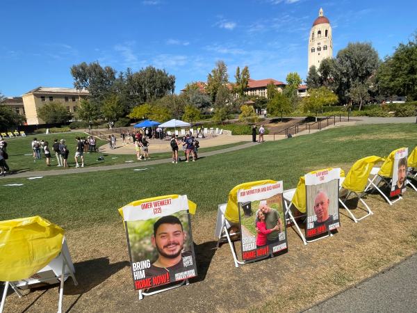 A circle of chairs surrounds Meyer Green at Stanford, each chair draped with the portrait of a hostage held by Hamas.