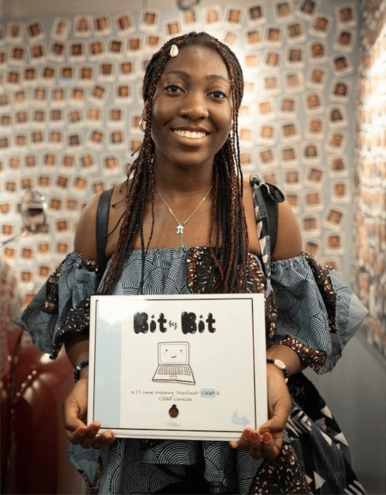 Ecy King poses with a copy of her CS 106A-themed graphic novel, "Bit By Bit."