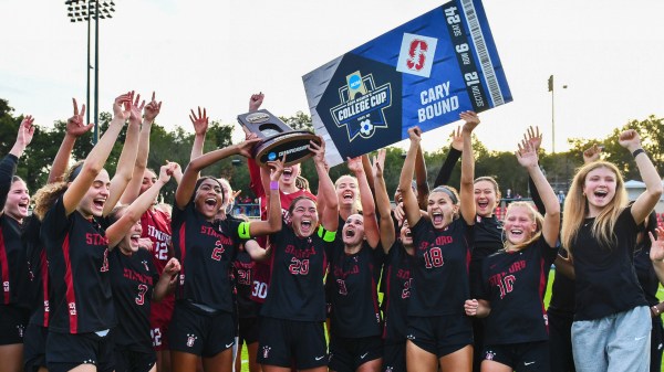 Soccer players hold trophy and sign in the air.